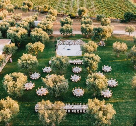 bride and groom walking between tables in olive grove at wedding venue in puglia masseria don luigi