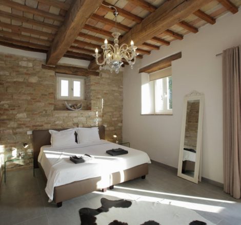 high wooden beam ceiling in master bedroom with stone walls and balcony