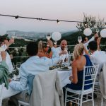 wedding guests raising a glass to the bride and groom whilst dining al fresco at Italian wedding venue at sunset