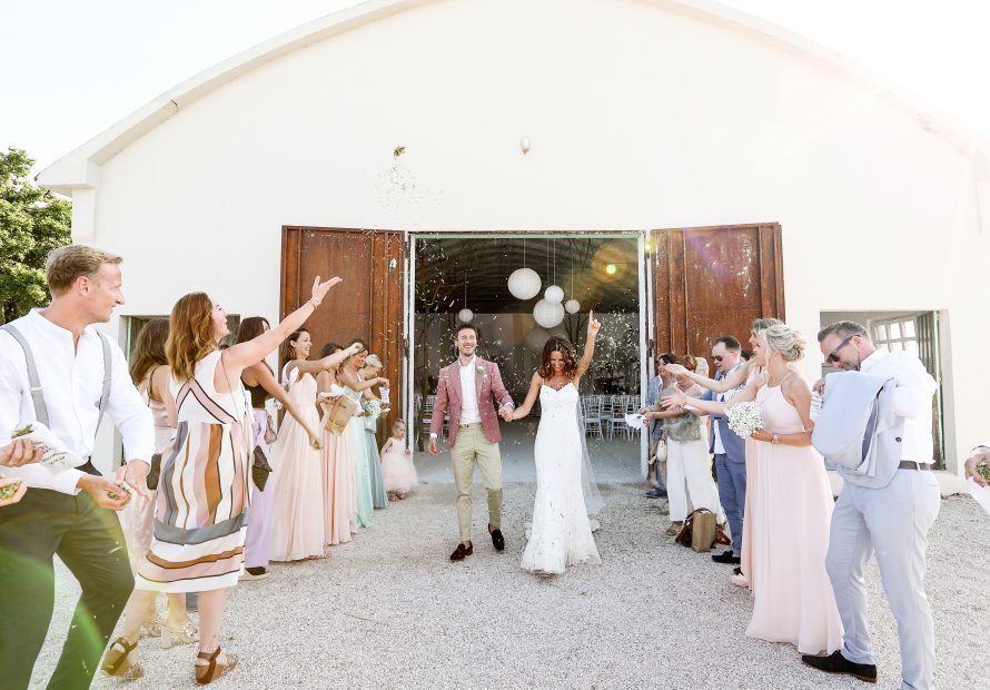bride and groom celebrating as they exit the indoor wedding ceremony at Italian estate surrounded by guests throwing confetti