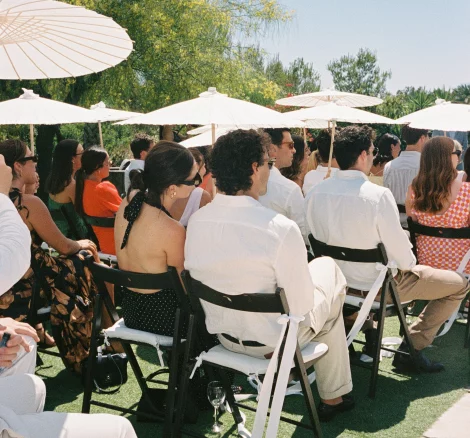 Guests sitting down at the aisle with umbrellas at wedding venue CasaNovaEstate