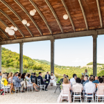 gran overhead barn style building with 100 wedding guests seated for wedding ceremony in Italy