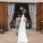 Bride and groom walking in through a curtain entryway to the wedding reception