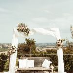 Ceremony archway with draped white chiffon fabric and flowers at Italian wedding venue