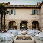 Stone courtyard at Italian country house wedding venue with wedding circular tables laid up for wedding breakfast