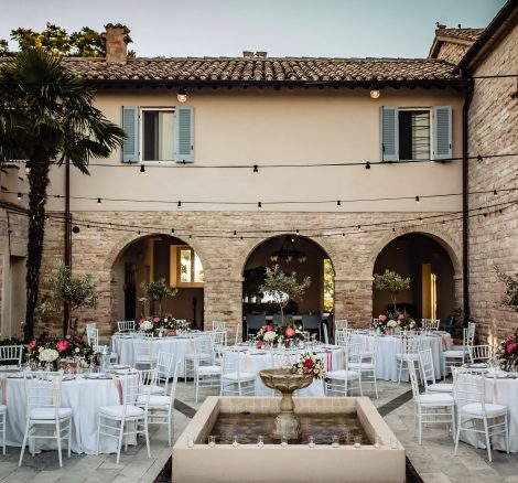 Stone courtyard at Italian country house wedding venue with wedding circular tables laid up for wedding breakfast