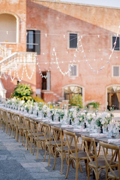long wedding table with wooden chairs and simple green foliage at Italian wedding venue masseria spina