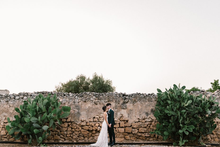 bride and groom stood together between Puglia cacti at Italian wedding venue masseria spina