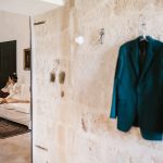 grooms blue blazer hung up against the stone wall at Italian wedding venue masseria spina