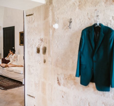 grooms blue blazer hung up against the stone wall at Italian wedding venue masseria spina