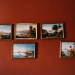 red wall with jumbled antique frames photographs hung at Italian wedding venue