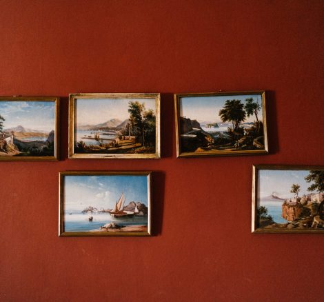 red wall with jumbled antique frames photographs hung at Italian wedding venue
