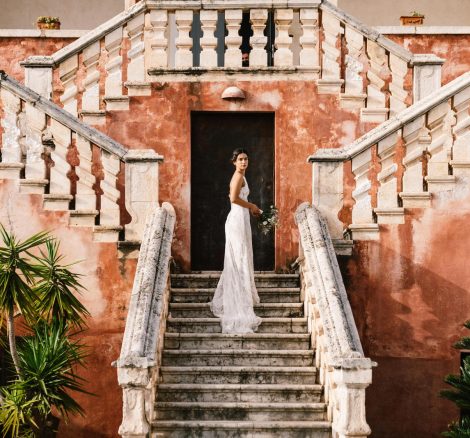 bride stood on the exterior steps with her train hanging over the below steps at Italian wedding venue masseria spina