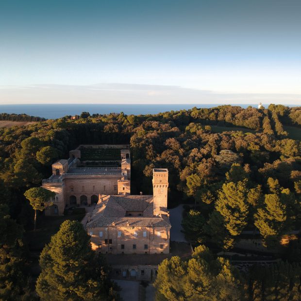 aerial view of Italian castle wedding venue amongst the trees beside the sea