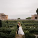 Bride and groom stood together in the manicured gardens at Italian wedding venue Villa Imperiale Pesaro