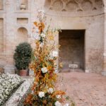 autumnal floral arrangement for an Italian wedding ceremony with white pillar candles