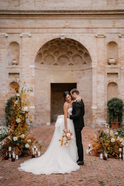 bride and groom stood together in front of beautiful old stone archway at Villa Imperiale in Italy