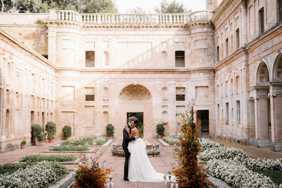 bride and groom stood together in the courtyard surrounded by stone walled garden at Italian wedding venue Villa Imperiale Pesaro