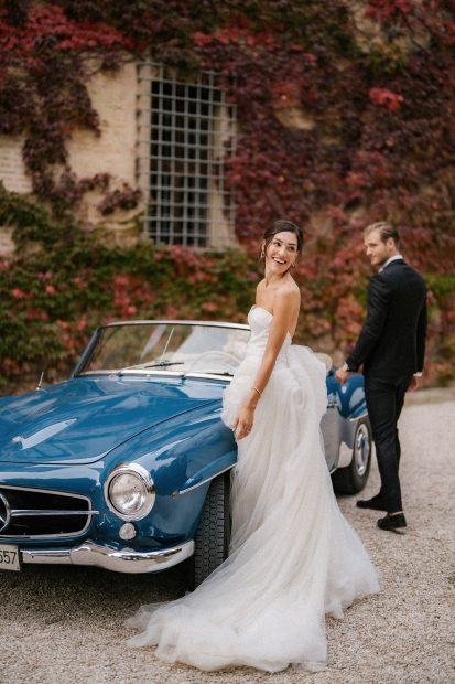 bride and groom stood alongside a old fashioned blue convertable wedding car outside the entrance at Italian wedding venue Villa Imperiale