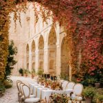 wedding table set up with autumnal florals against the stone arched cloisters