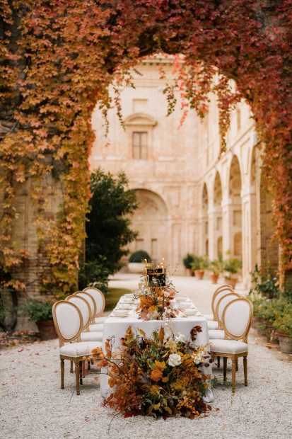 elegant table laid up for an Italian wedding under an archway of autumnal florals