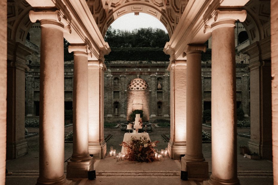 lights illuminating 4 stone pillars and cake display at Italian wedding venue Villa Imperiale