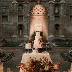 white tiered wedding cake surrounded by an autumnal floral display at Italian wedding venue Villa Imperiale