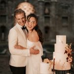 Bride and groom laugh and hug as they have a photo beside they 3 tier wedding cake at Italian wedding venue Villa Imperiale