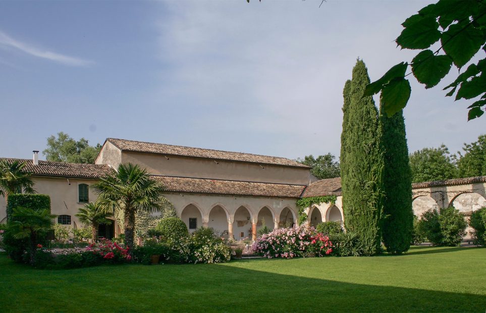 view across the green grass up towards the light pink stone exterior of Italian wedding venue convent dell'Annunciata
