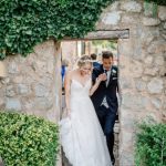 bride and groom walking in together hand in hand through a stone archway at ca's xorc wedding venue in mallorca