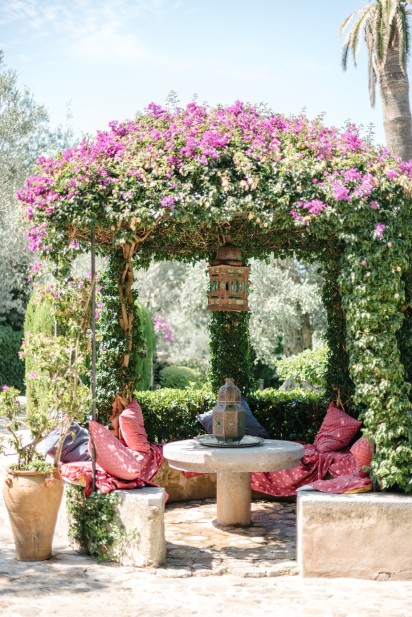 pink flowers cascade over the stone seating area outside luxury wedding venue ca's xorc in mallorca