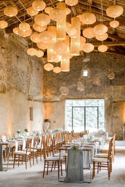 long rectangular wedding tables in old barn with grey linen table runners at wedding venue le Petit Roulet in Luberon france