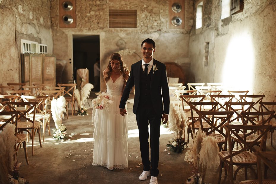 bride and groom walking back down the aisle in stone barn at French wedding venue le Petit Roulet