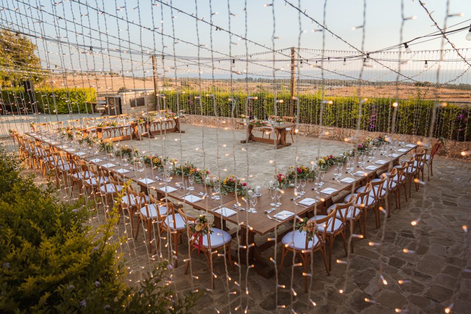 c shape wooden tables under draped fairy lights at wedding venue in Cyprus liopetro