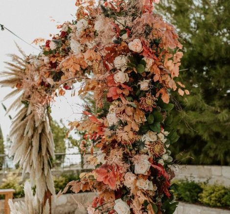 flowers and pampas grass in pinks and neutral tones over wooden square ceremony aisle arch at wedding venue in Cyprus liopetro