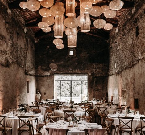 wedding tables under rattan hanging lights in renovated barn at French wedding venue le petit roulet