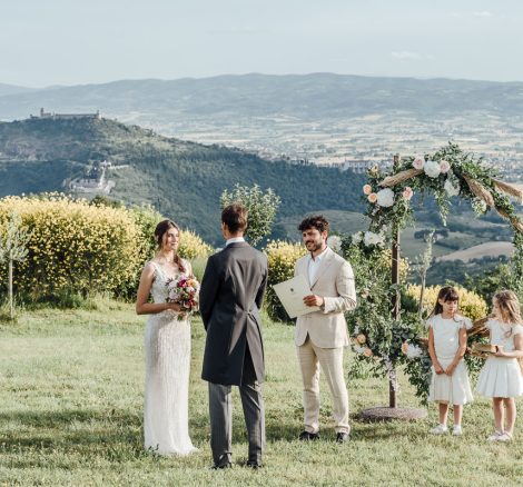 bride and groom and children wedding ceremony with umbria hillside backdrop at wedding venue in italy castello di petrata