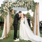 bride and groom say I do under floral arch outside at wedding venue in Tuscany Italy Borgo Stomennano