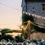 festoon lighting strung above wedding reception al fresco dining at unqiue wedding venue in italy castello di petrata