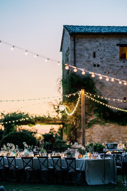 festoon lighting strung above wedding reception al fresco dining at unqiue wedding venue in italy castello di petrata