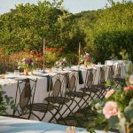 wooden wedding chairs and long linen laid tables outside at wedding venue in italy castello di petrata