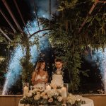 bride and groom with fireworks in the background cutting the cake at wedding venue in italy