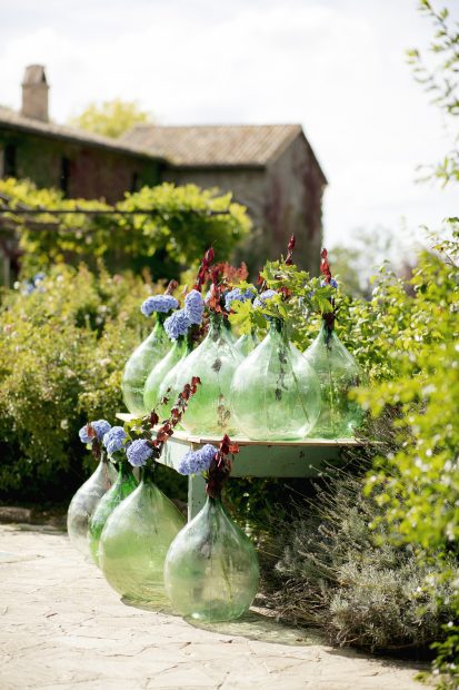 collection of large green glass florists bottles as wedding decor at wedding venue in italy castello di petrata