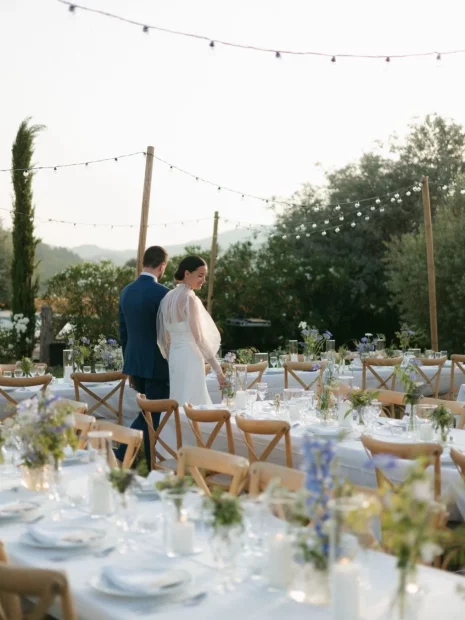Image of married couple walking around tables looking at decorations at wedding venue Clos du Tuilier