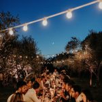 wedding guests dining outside under fairy lights at wedding venue in france provence le domaine du rey