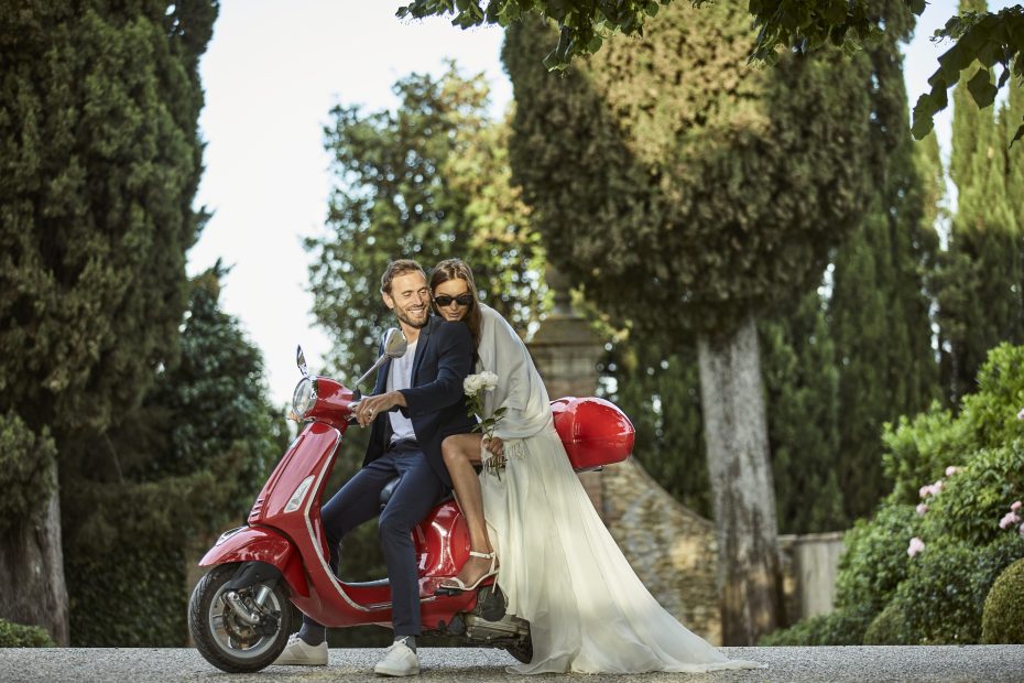 bride and groom on red scooter at luxury wedding venue in Tuscany COMO Castello Del Nero