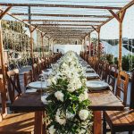 wooden chairs and fairy lights overhead at open air wedding venue in Santorini Greece