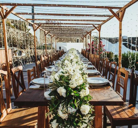 wooden chairs and fairy lights overhead at open air wedding venue in Santorini Greece