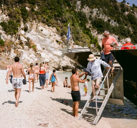 Image of wedding guests leaving a boat on a beach at wedding venue The Peligoni Club