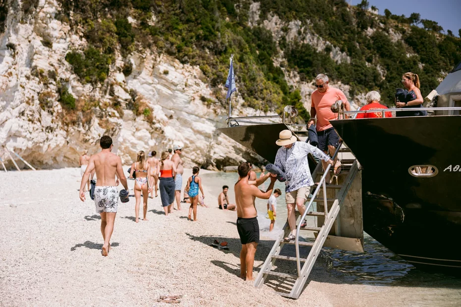 Image of wedding guests leaving a boat on a beach at wedding venue The Peligoni Club